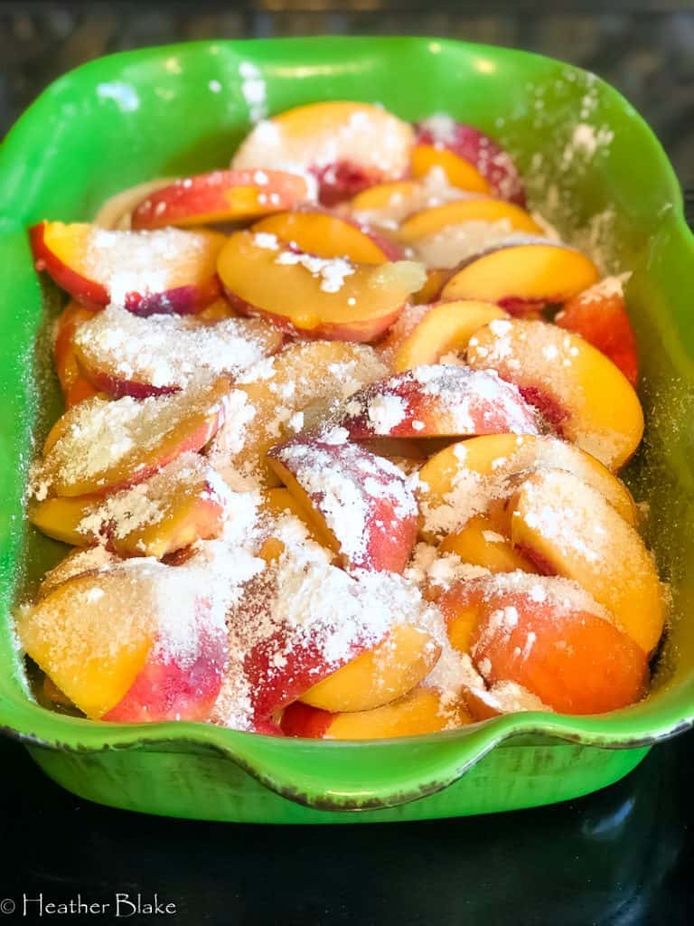A picture of peaches ready to be topped with the batter and candied almonds
