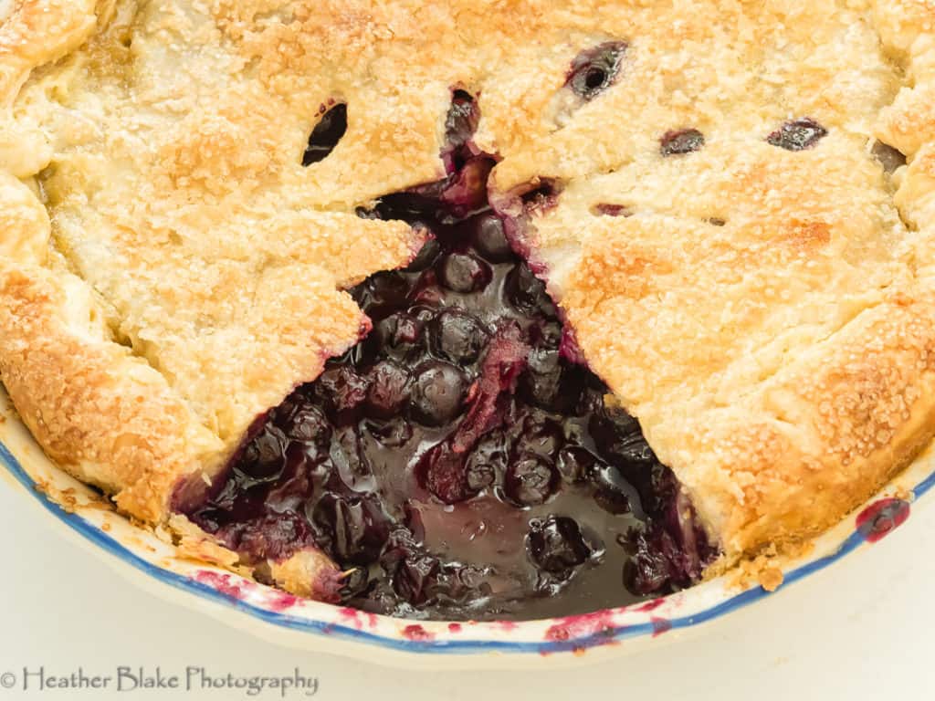 A picture of a whole blueberry pie with a slice cut out.